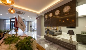 A modern hotel lobby with a reception desk, seating area, and wall clocks displaying times from Moscow, Istanbul, and Tokyo. - Beypalas Hotel (Beypazari)