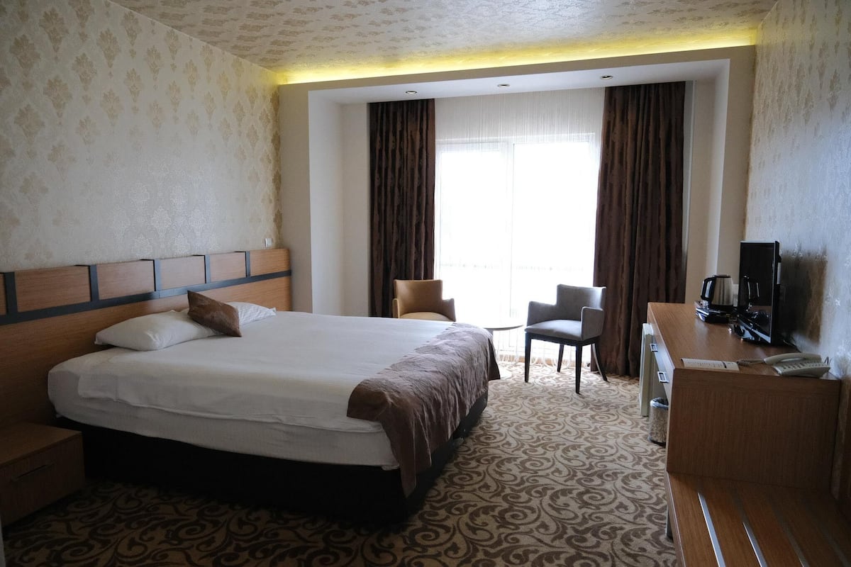 Una habitación de hotel con una cama grande, un escritorio con teléfono y una televisión.