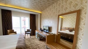 A hotel room with a bed, a desk with a TV, a chair, and a large mirror. - Sor Hotel Eskisehir (Eskisehir)