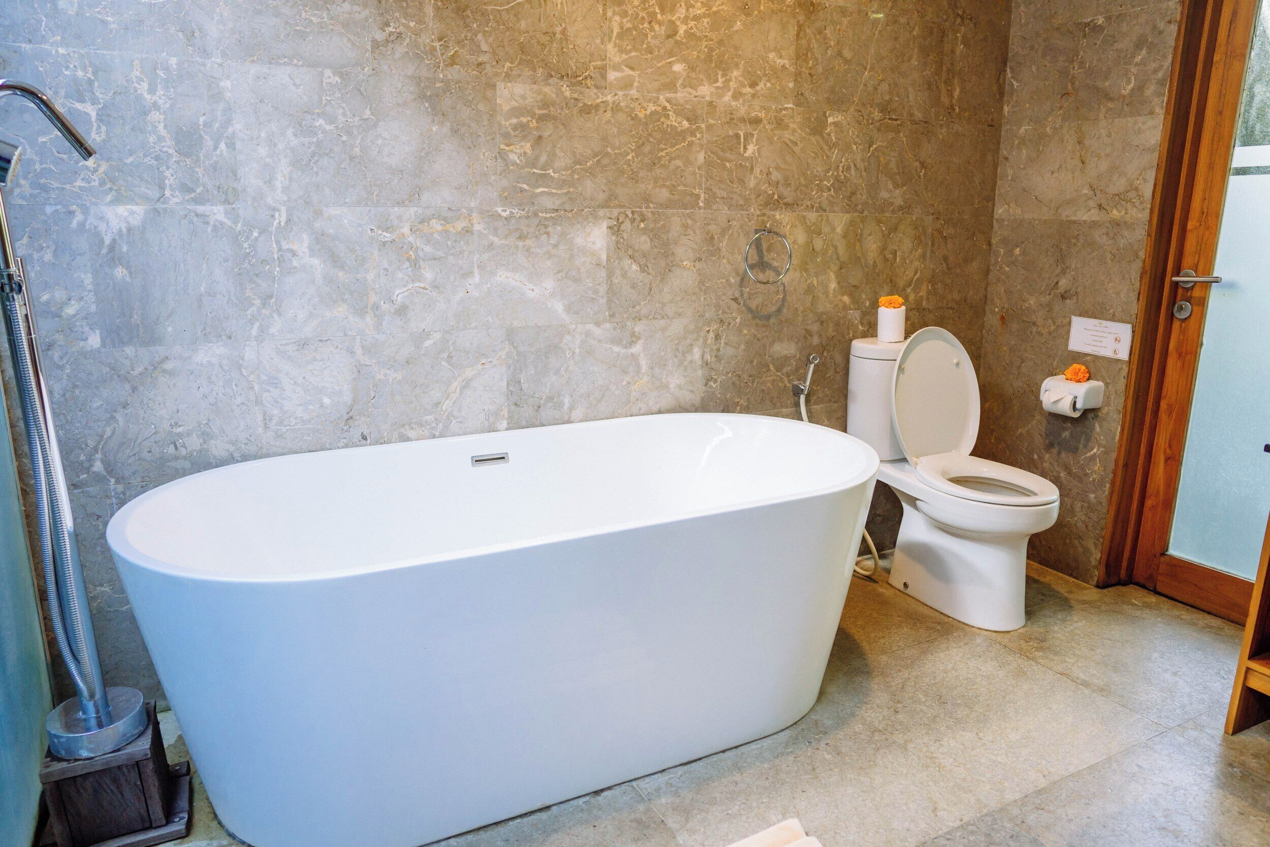 A bathroom with a freestanding bathtub, a toilet, and a showerhead.