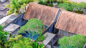 A residential area with multiple buildings, including a house with a tiled roof and a small garden area with various plants and a water feature. - Ume Sri Villas Ubud (Ubud)