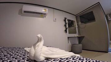 Una camera da letto moderna con un letto, un condizionatore d'aria a parete, uno specchio e uno sgabello.