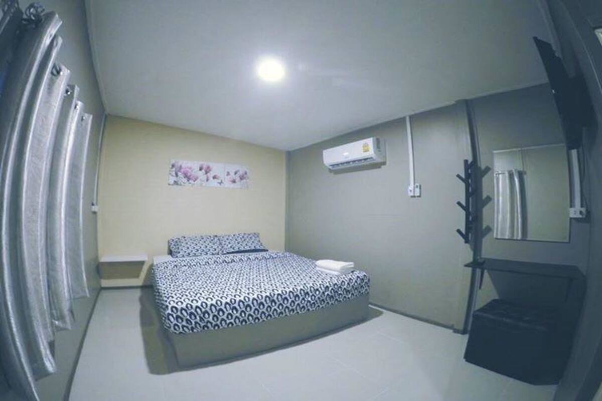 Ein Schlafzimmer mit einem Bett, einem kleinen Nachttisch, einer Wand-Klimaanlage und einem Spiegel.