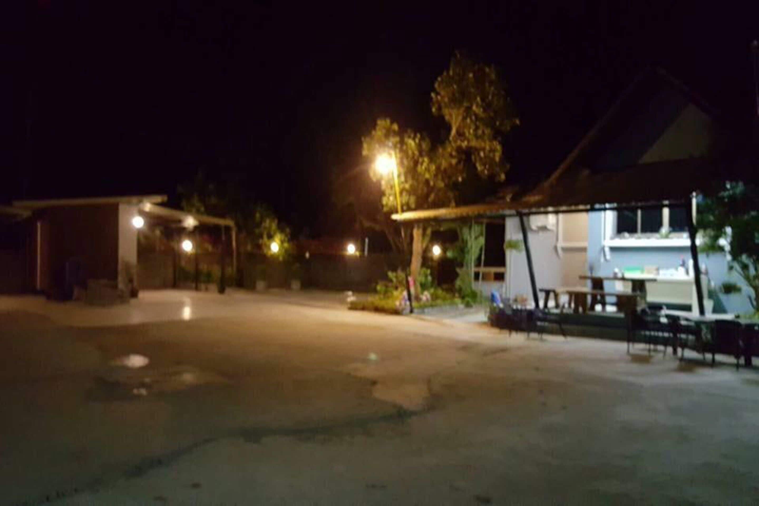 A nighttime view of a parking lot with a covered area and a building with a porch.