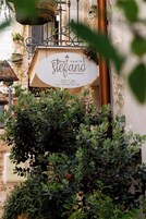 A sign for 'Santo Stefano' indicating a home and breakfast service, with operating hours and a contact number.