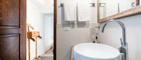 A bathroom with a wooden door, a white sink, a mirror, and a towel rack.