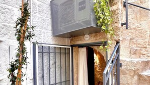 A narrow entrance with a metal gate, a small balcony with plants, and a stone wall. - Santo Stefano Home & Breakfast (Polignano a Mare)