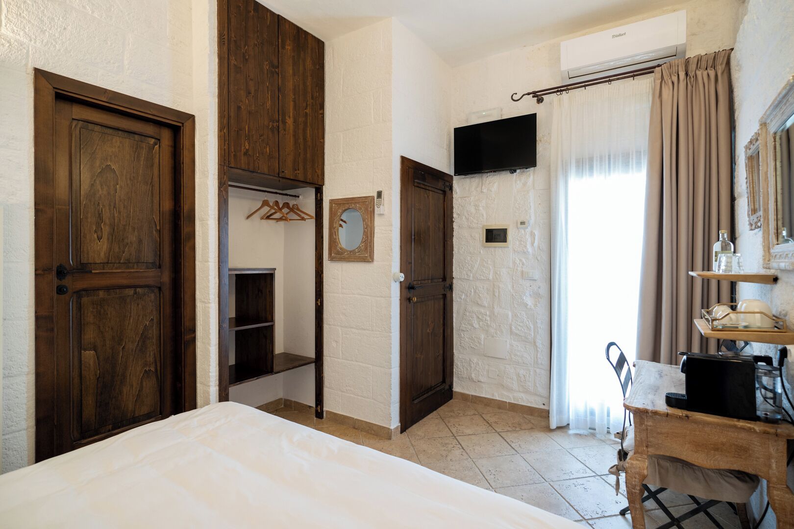 Ein Schlafzimmer mit einem Bett, einem Holzschrank, einem Spiegel und einem Fernseher.