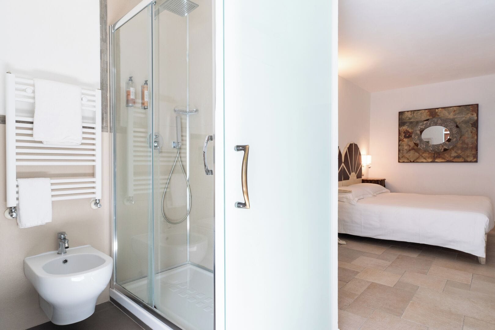 A modern bathroom with a glass shower enclosure, a bidet, and a towel rack.