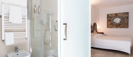 A modern bathroom with a glass shower enclosure, a bidet, and a towel rack.