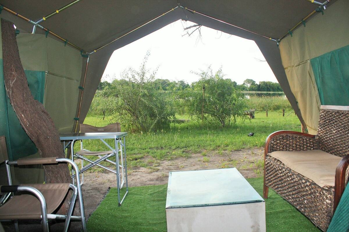 Una carpa con una mesa y sillas, una mesita auxiliar y un banco acolchado.