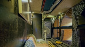 A train compartment with a bunk bed, a fan, and a small table with a plate. - LeuLeu Hostel 2 (Xuan Huong - Da Lat)