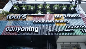 A signboard with various travel-related services including tours, mountain biking, canyoning, and transportation. - LeuLeu Hostel 2 (Xuan Huong - Da Lat)