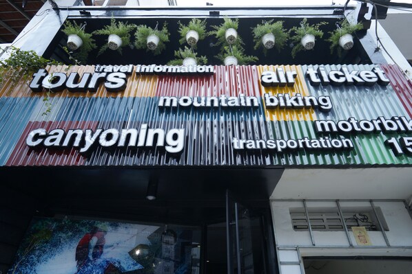 A signboard with various travel-related services including tours, mountain biking, canyoning, and transportation.