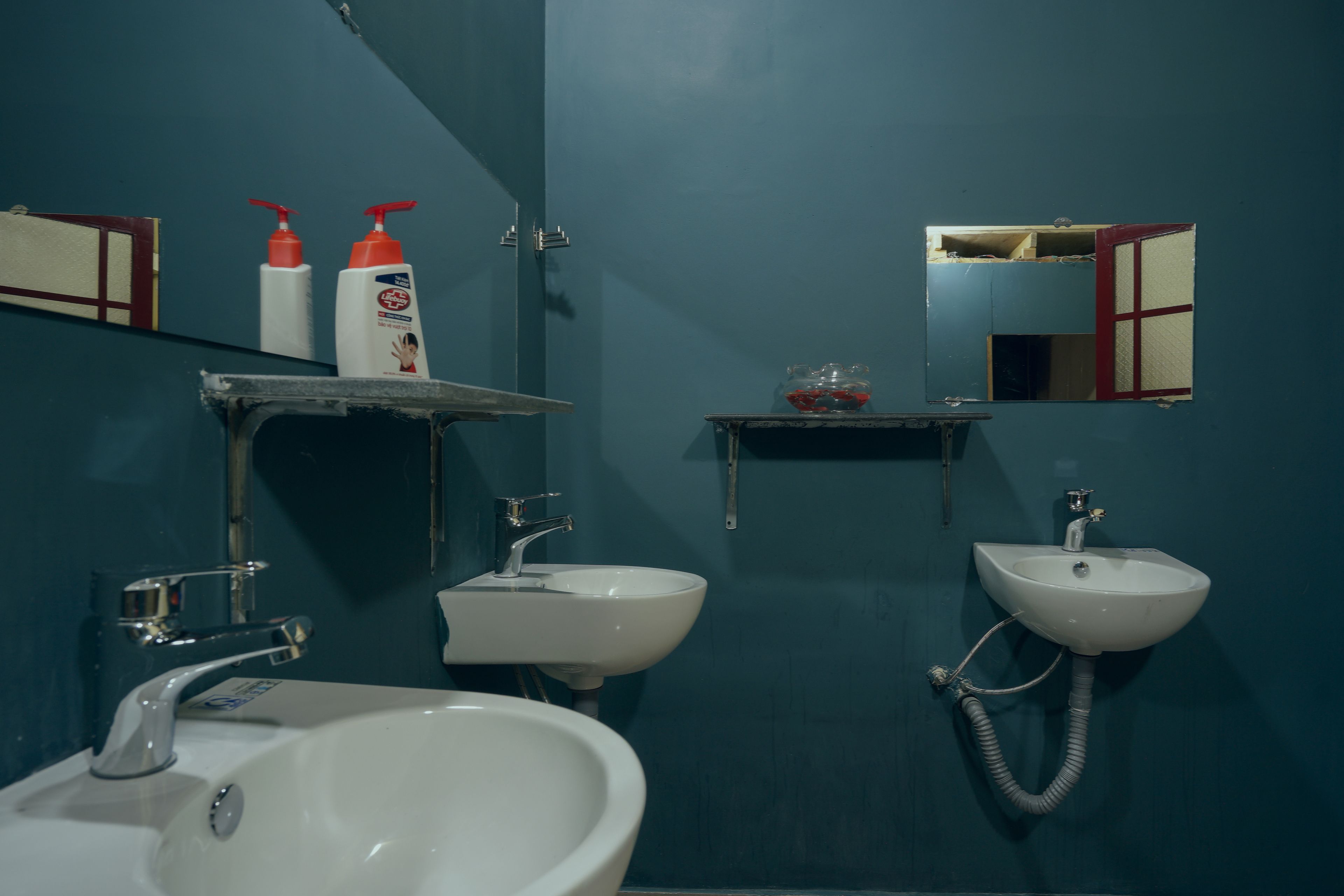 Un baño con dos lavamanos, un espejo y una repisa con artículos de aseo.