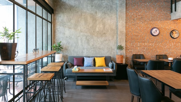Un café moderne avec un mur en briques, de grandes fenêtres et un mélange de meubles en bois et en métal.