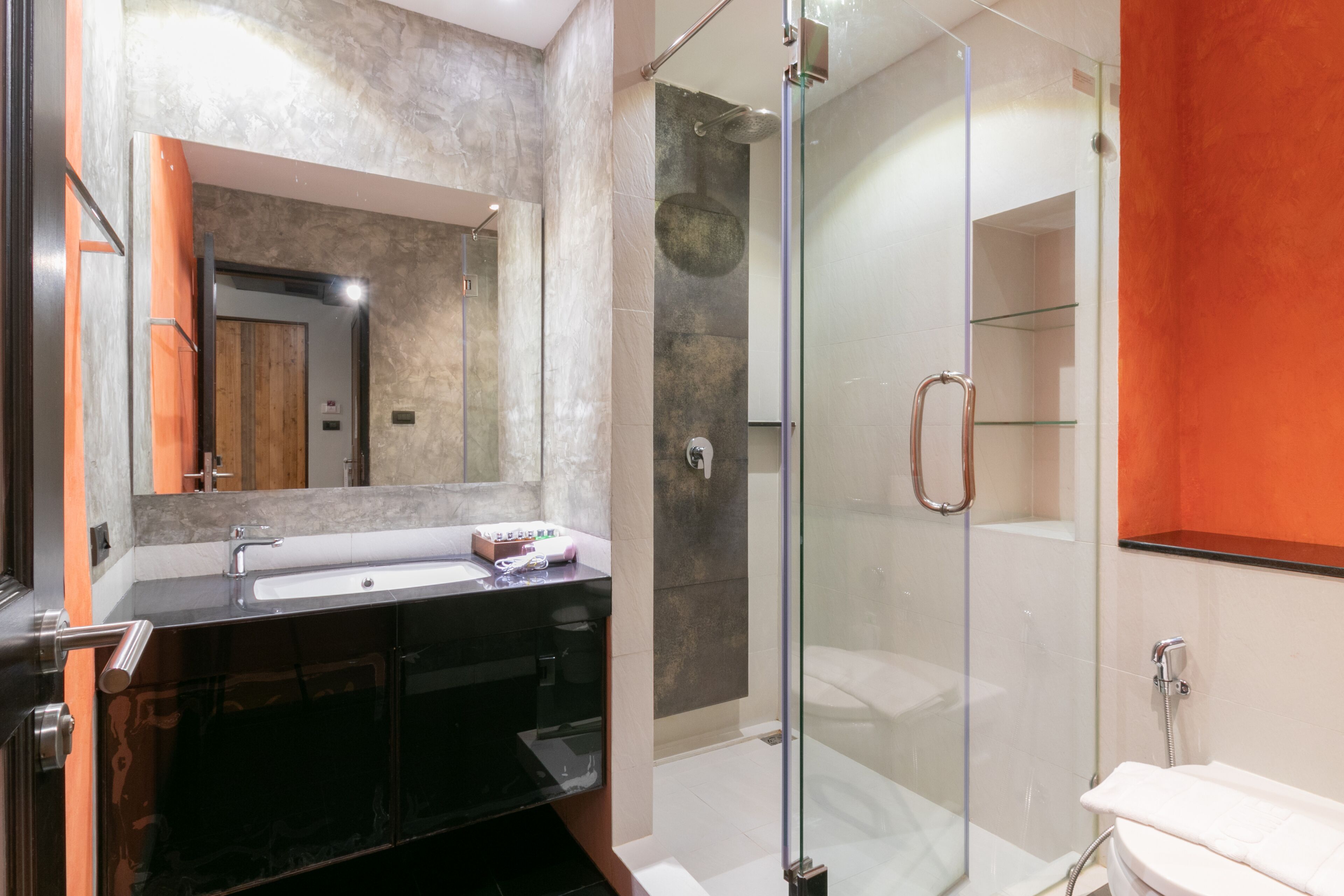 Une salle de bain moderne avec une douche à parois de verre, un grand miroir et un meuble-lavabo noir.