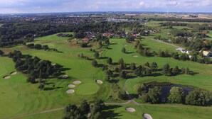 Vista aérea de un campo de golf con varios búnkeres, rodeado de zonas residenciales y árboles.