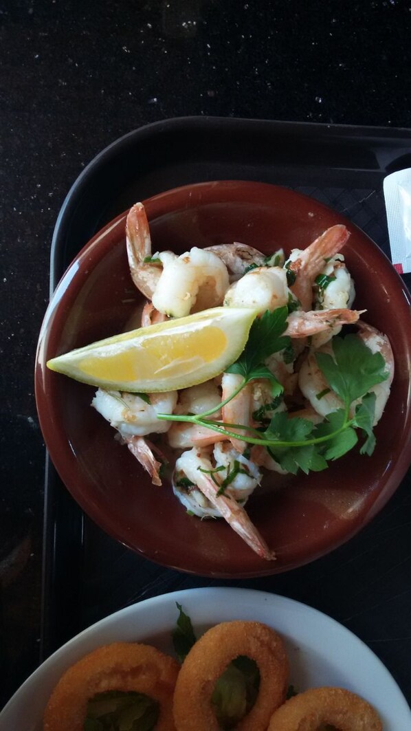 Un tazón de ensalada de camarones, aderezada con limón y perejil.