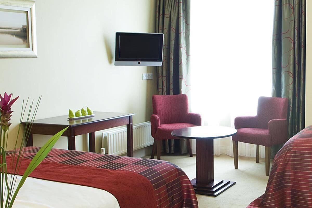 Une chambre d’hôtel avec deux lits, une télévision, une petite table, deux chaises et une vue sur l’extérieur.