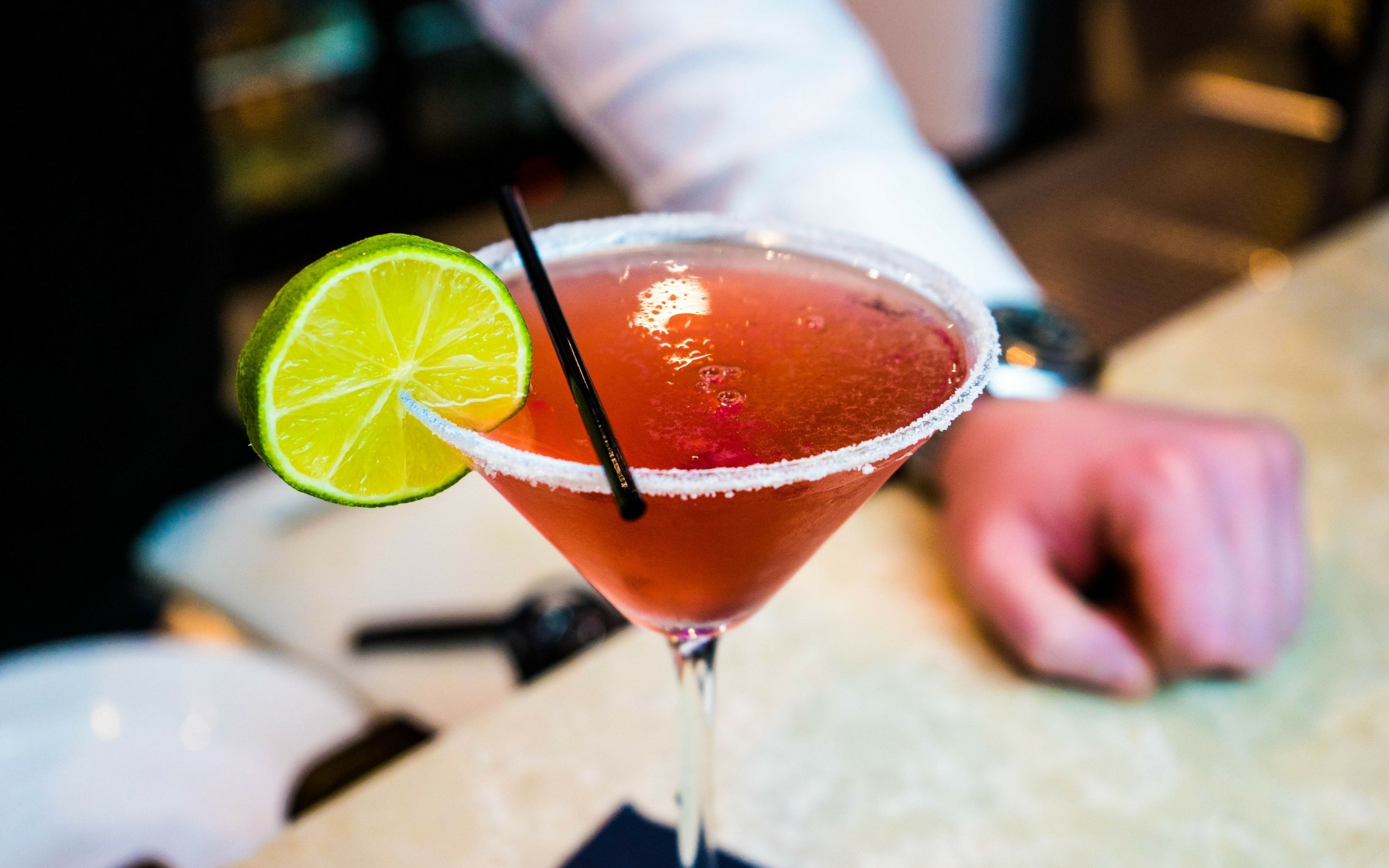 Ein Cocktail mit Limettenscheibe und Salzrand, gehalten von einer Person.