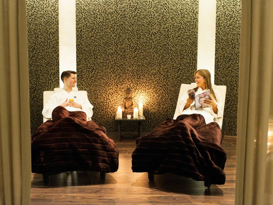 A room with two reclining chairs, a Buddha statue, and candles.