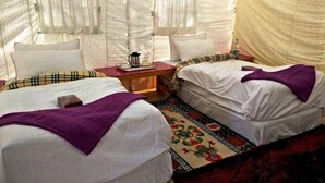 Un intérieur chaleureux avec deux lits, une petite table avec une bouilloire et un tapis à motifs.