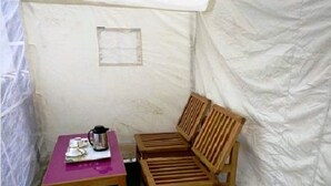 Une petite pièce fermée, avec un banc en bois et une table sur laquelle se trouve une cafetière.
