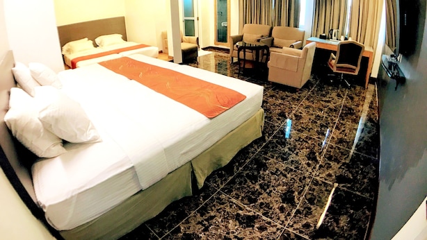 A hotel room with a large bed, a desk, a chair, and a sofa. - Lux Private Hotel (Petaling Jaya)