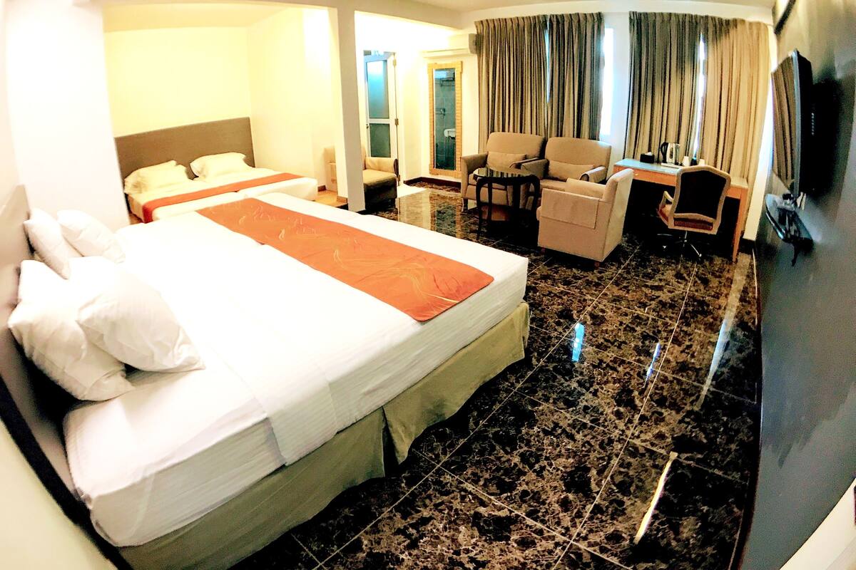 A hotel room with a large bed, a desk, a chair, and a sofa.