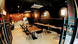 A restaurant interior with multiple tables and chairs, a counter area, and a brick wall. - Lux Private Hotel (Petaling Jaya)