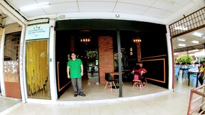 A restaurant with a curved entrance, a sign indicating room availability, and a seating area with tables and chairs. - Lux Private Hotel (Petaling Jaya)