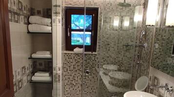 Une salle de bain moderne dotée d’une douche à parois de verre, de toilettes et de deux lavabos.