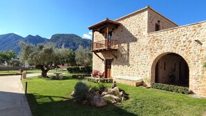 A stone building with a balcony, an archway, and a garden with rocks and trees. - Mystras Grand Palace Resort & Spa (Sparta)