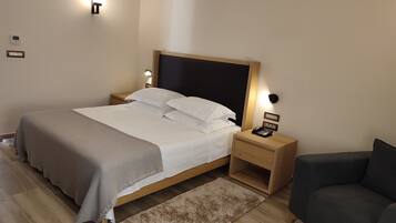 A neatly arranged bedroom with a bed, bedside tables, a telephone, and a sofa.