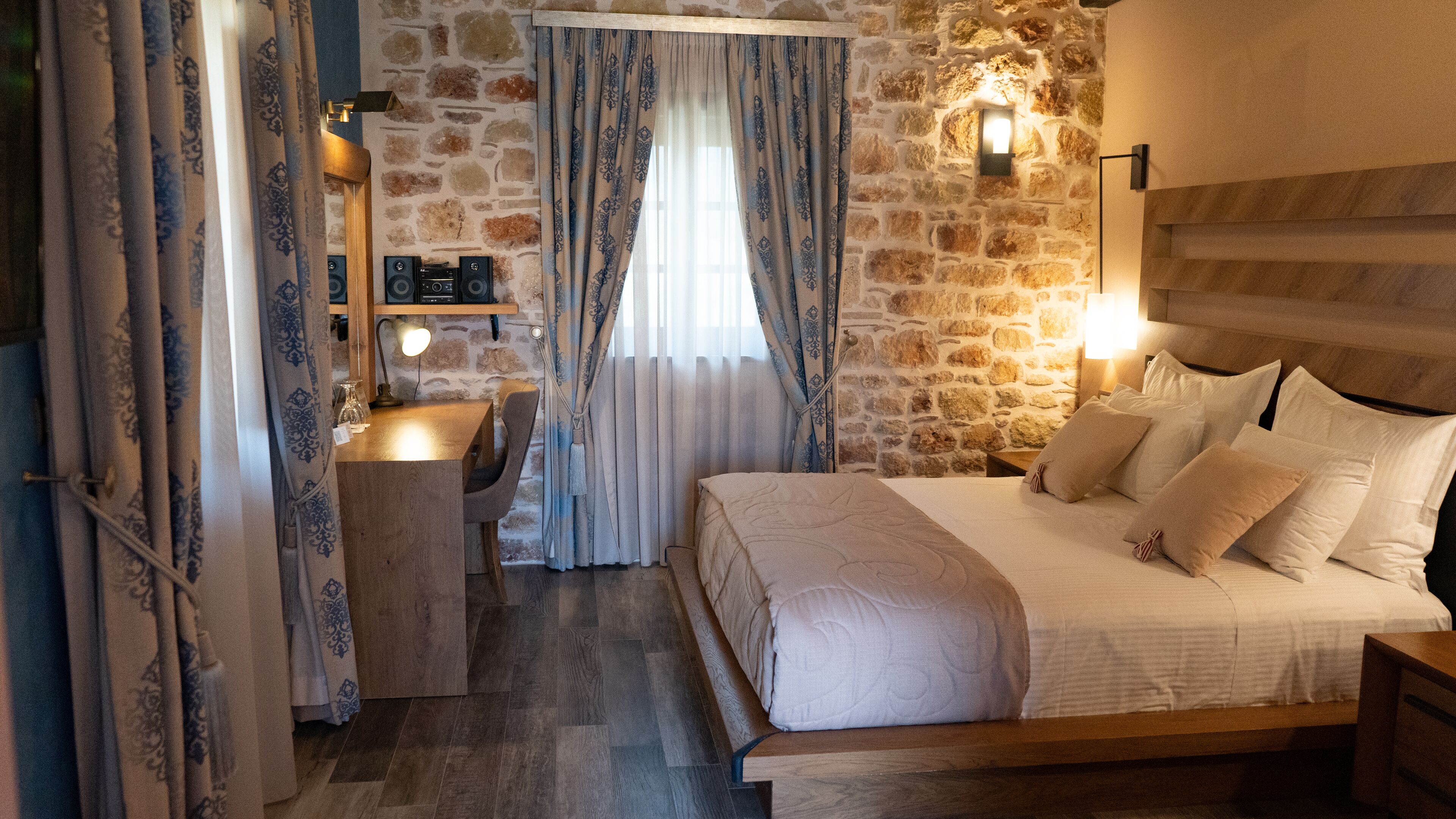 Un dormitorio acogedor con pared de piedra, cama de madera y escritorio con lámpara.