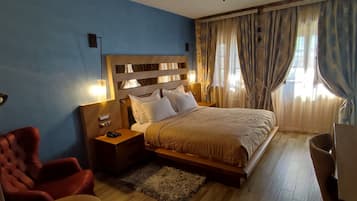 A hotel room with a bed, bedside table, lamp, chair, and a desk with a chair.