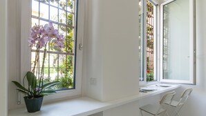 Una habitació amb un davell de finestra, una planta en test i dues cadires blanques.