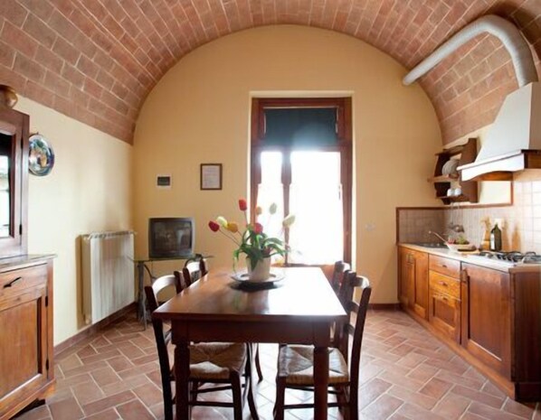 Una cocina con un arco de ladrillo, una mesa de comedor con sillas y una ventana con vistas.