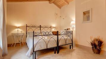 A bedroom with a metal bed frame, a bedside table with a lamp, a small bedside table with a lamp, and a potted plant.