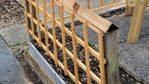 Un espace extérieur aménagé avec des meubles en bois, comprenant une table et des chaises, le tout entouré d’une clôture en bois.