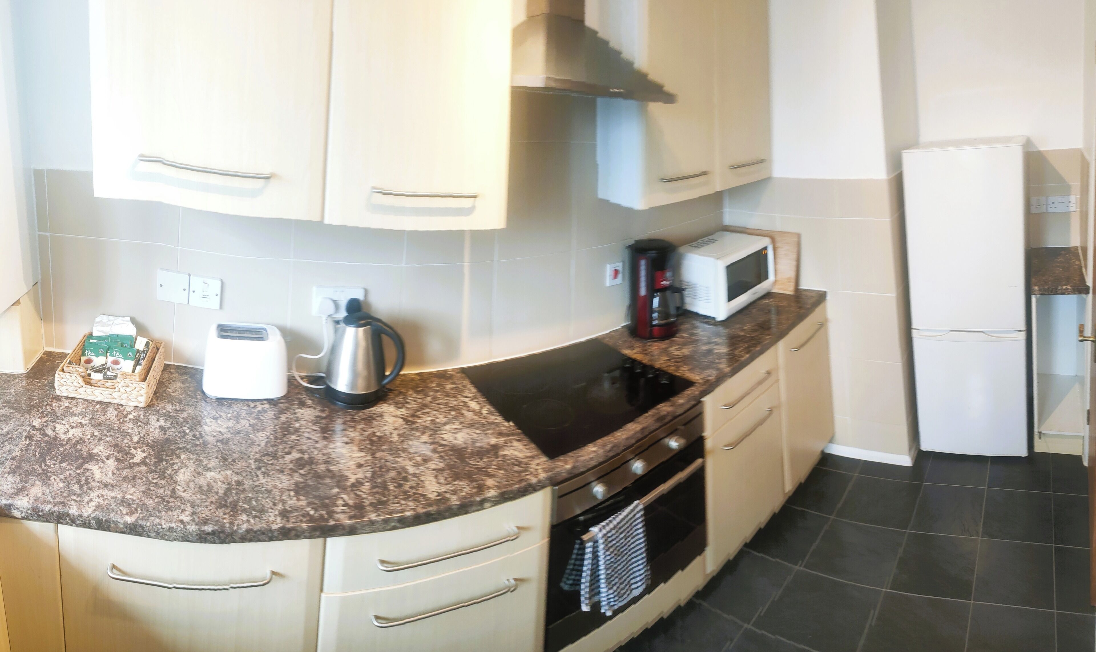 A kitchen with a granite countertop, stainless steel appliances, and light-colored cabinetry.