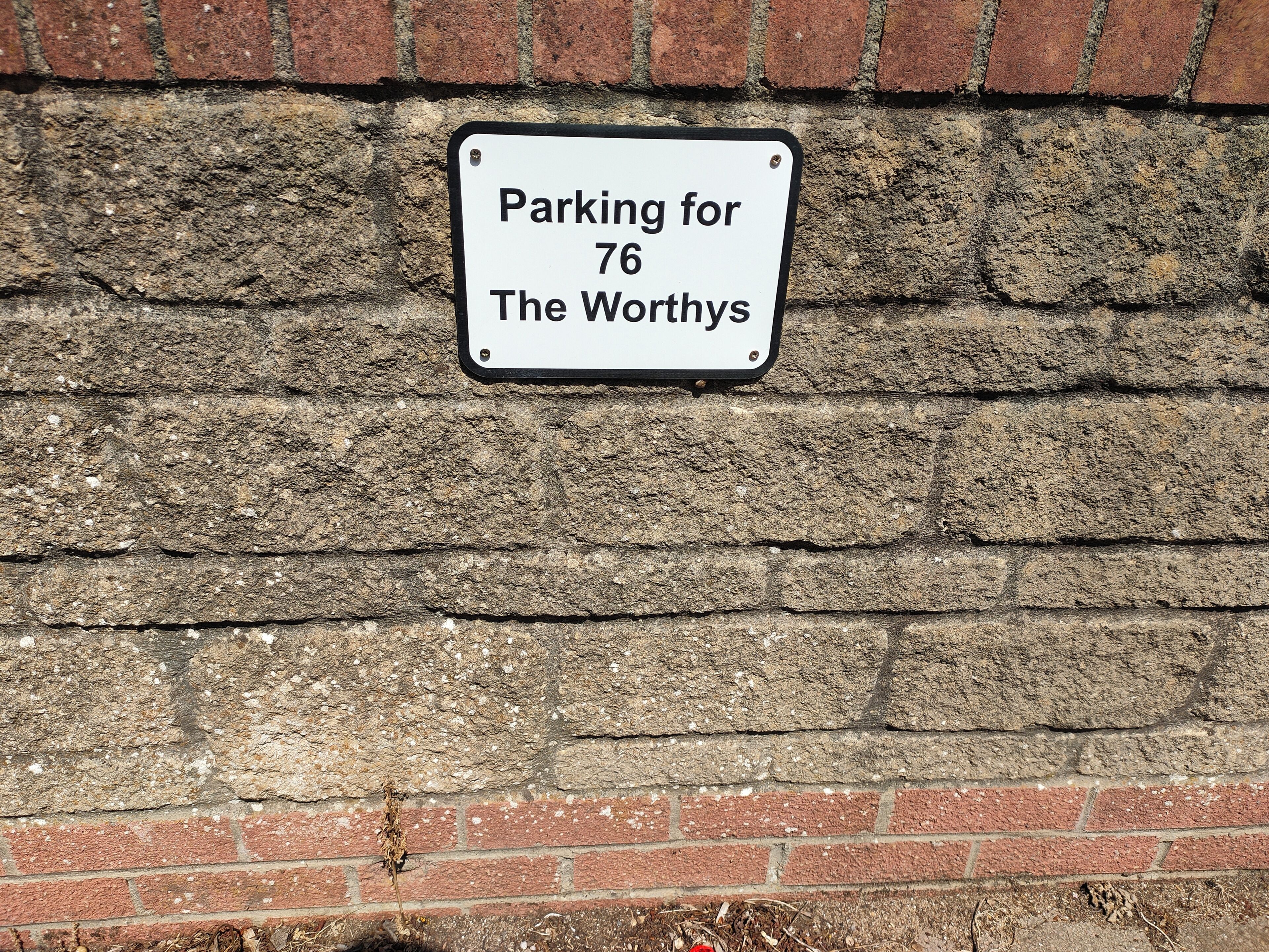 A sign on a brick wall indicating parking for The Worthys.