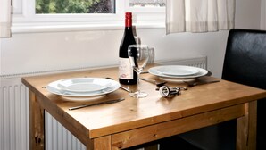Une table en bois avec deux assiettes blanches, une bouteille de vin et un verre à vin.