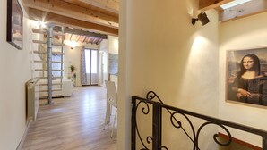 A wooden interior with a staircase, a painting of the Mona Lisa, and a view into a dining area. - Monna Lisa Apartment (Florence)