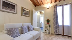 A modern living room with a white sofa, patterned cushions, and two framed artworks on the wall. - Monna Lisa Apartment (Florence)