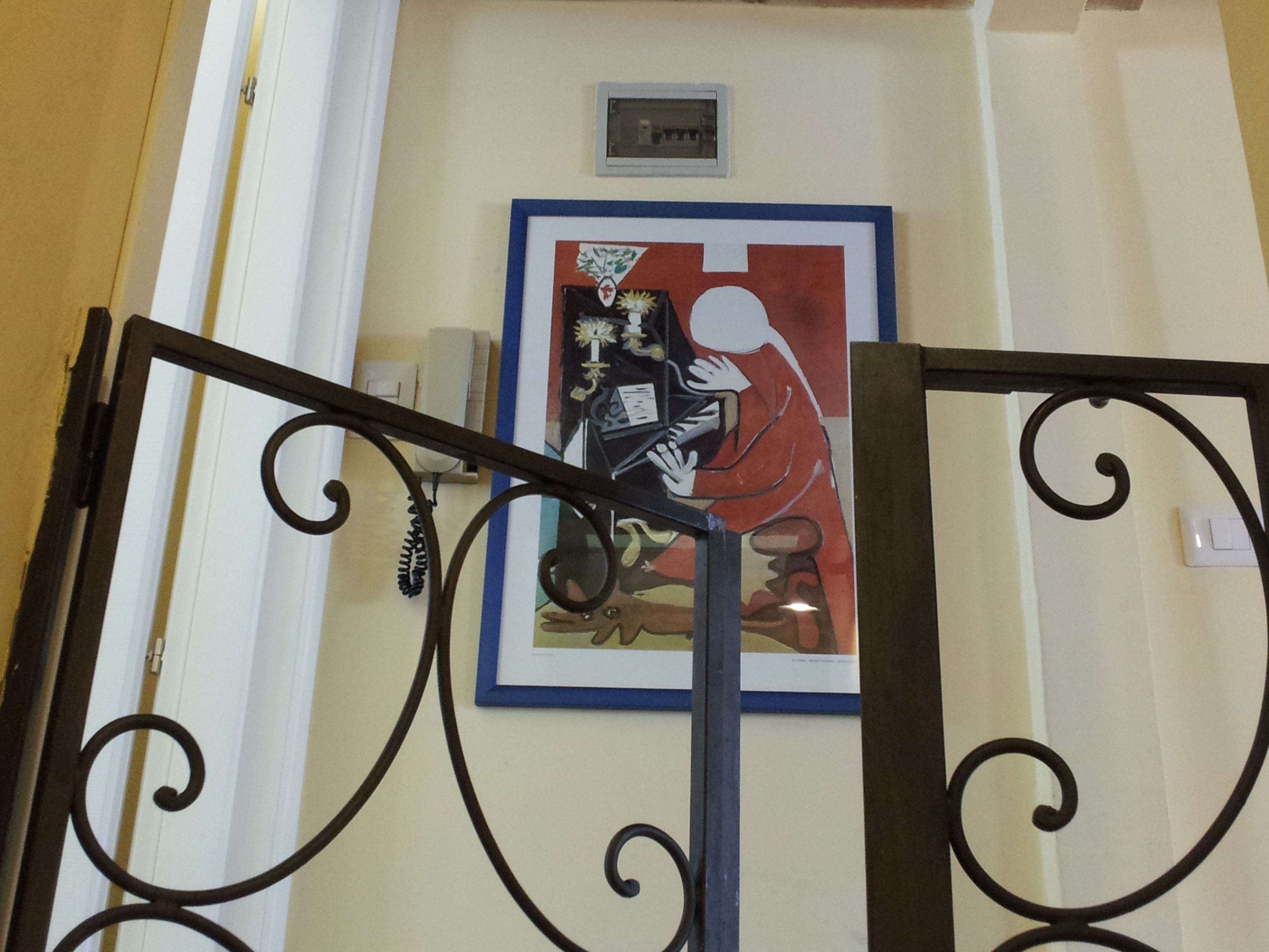 Una escalera con barandilla de metal y una obra enmarcada en la pared superior.