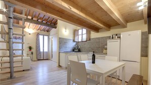 A modern kitchen with white cabinets, a stone backsplash, and a wooden ceiling. - Monna Lisa Apartment (Florence)