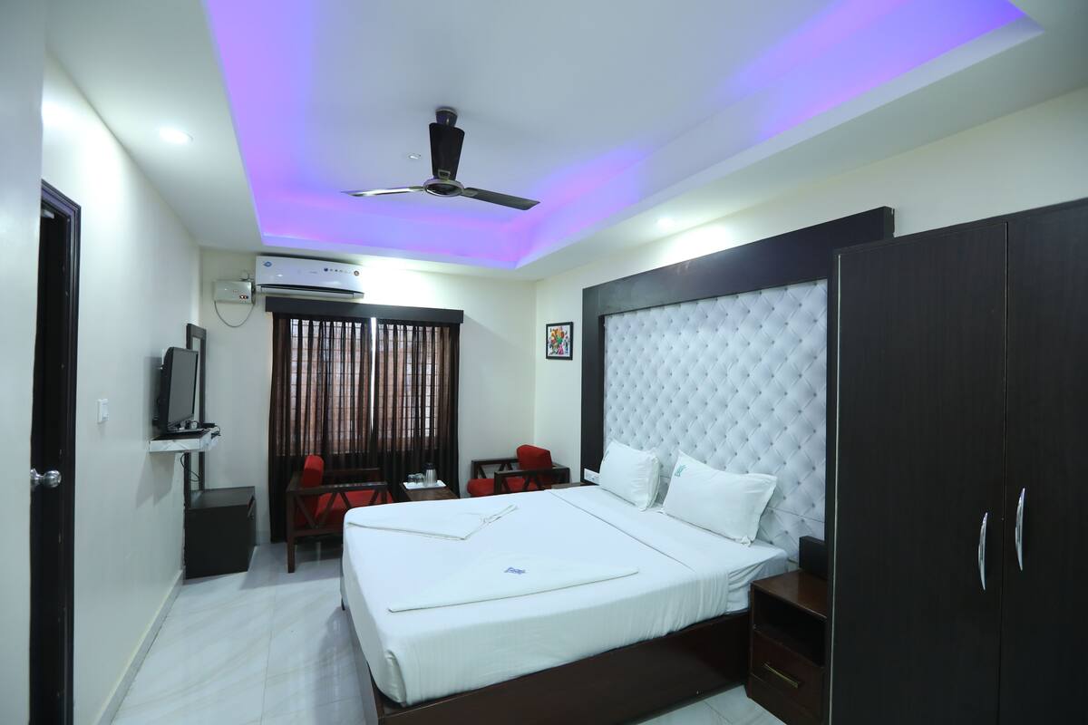 A hotel room with a bed, a desk, a chair, a wardrobe, and a ceiling fan.