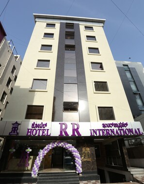 Un edificio de hotel con un cartel que dice "Hotel RR International" y un logotipo con una corona.